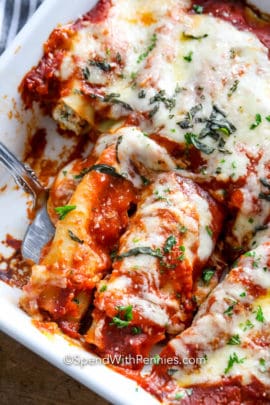 Cheesy cannelloni being scooped up with a metal spatula