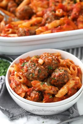 Cheesy baked penne in a white bowl garnished with parsley