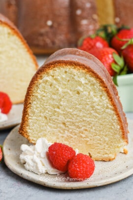Cream Cheese Pound Cake on a plate with raspberries and whipped cream