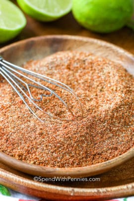 Fajita seasoning in a wooden bowl with limes in the background