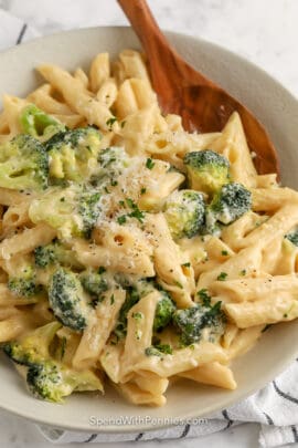 broccoli pasta on a white plate with a wooden spoon