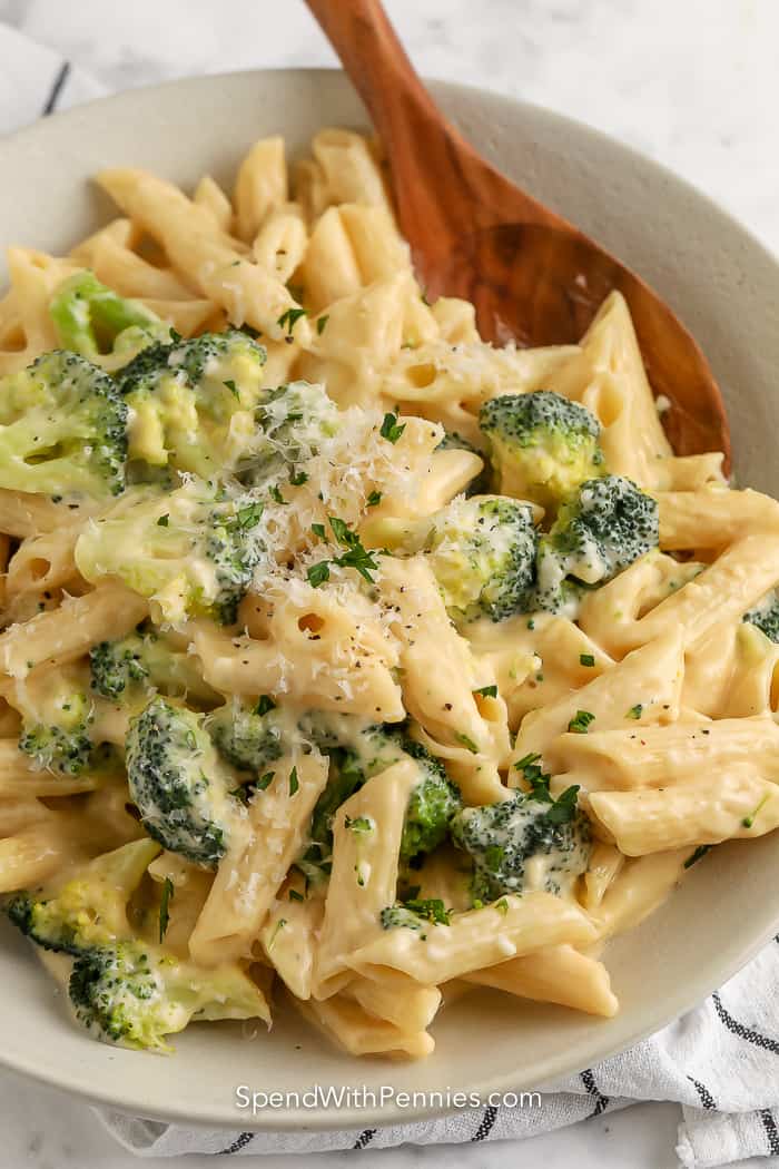 broccoli pasta on a white plate with a wooden spoon