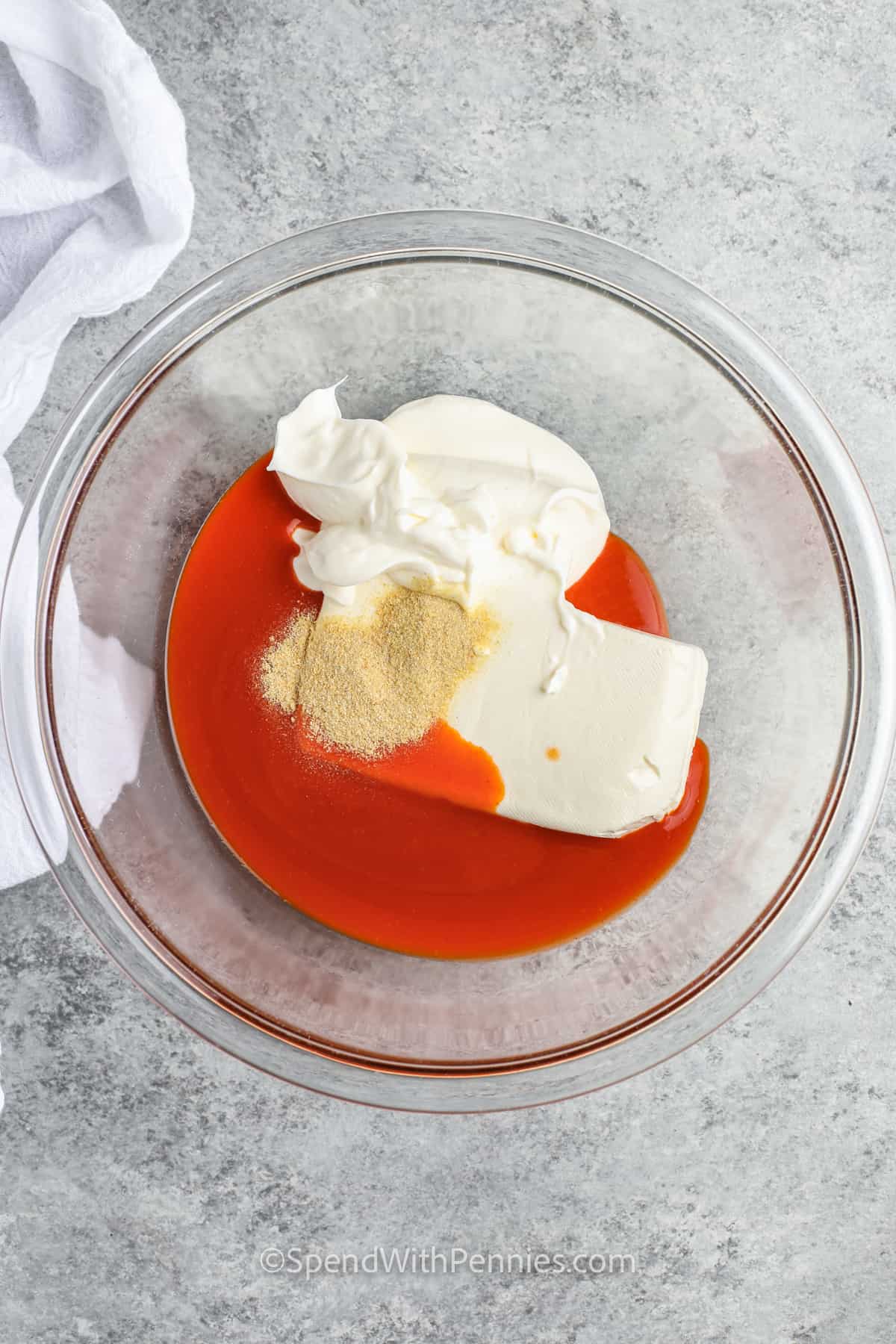 adding buffalo sauce to cream cheese and sour cream with seasonings to make The Best Buffalo Chicken Dip